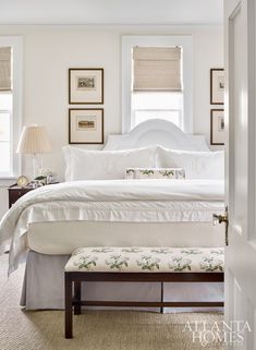 a white bed sitting in a bedroom next to a window with pictures on the wall