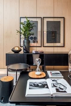 a living room with pictures on the wall and coffee table in front of an open book