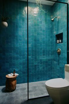 a blue tiled bathroom with a toilet and shower