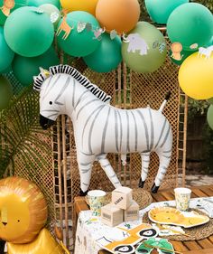 a zebra statue sitting on top of a wooden table next to a bunch of balloons