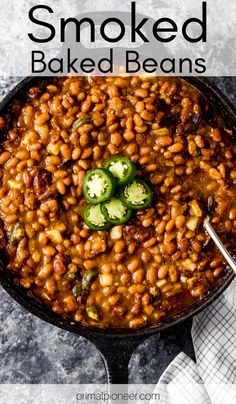 a skillet filled with baked beans and jalapenos on top of a table