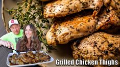 a man and woman sitting next to a plate of grilled chicken thighs