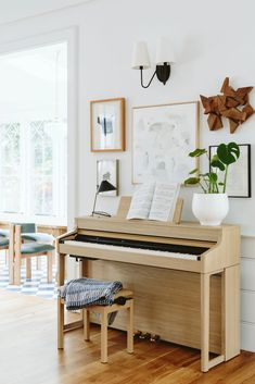 a piano sitting in the middle of a living room next to a wall with pictures on it