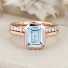 an aquamarinee and diamond engagement ring on top of a white flower