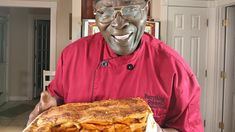 a man in a red shirt is holding a large piece of food on a plate