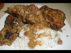 meat and rice on a white plate with gravy over the top is ready to be eaten