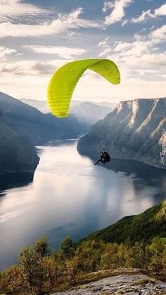 a person paragliding over a large body of water with mountains in the background