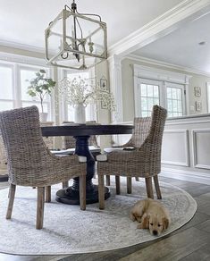 a dog laying on the floor in front of a dining room table with chairs and a chandelier