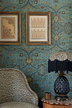 a leopard print chair next to a table with a lamp on it and two framed pictures