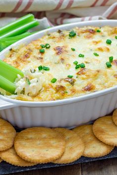 a casserole dish with celery, cheese and crackers on the side