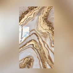 an abstract painting with gold and white paint on it's surface is seen in this image