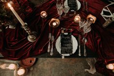 an overhead view of a table with candles and place settings on it, surrounded by red velvet