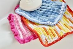 three crocheted dishcloths and a soap dispenser on a white surface