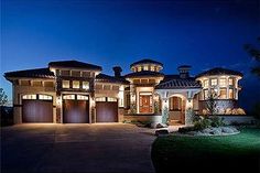 a large house lit up at night with lights on the front and garage doors open