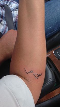 a person sitting in a car with a tattoo on their arm that reads, love