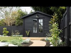 a small black house in the middle of a garden