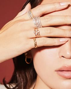 a woman holding her hands up to her face with two rings on top of her head