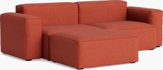 an orange couch and ottoman sitting next to each other