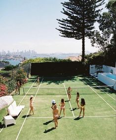 several women in bathing suits playing tennis on a grass court