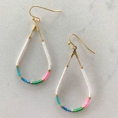 a pair of earrings with multicolored beads hanging from it's earwires