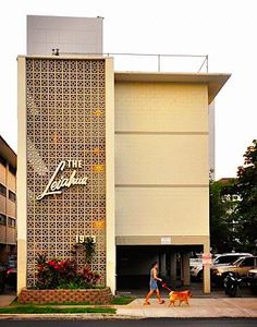 a person walking a dog in front of a building with a large sign on it