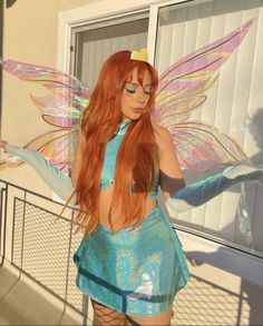 a woman dressed as a fairy with long red hair wearing a blue dress and wings