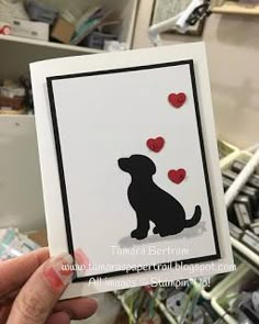 a person holding up a card with a dog and hearts on it in front of some shelves