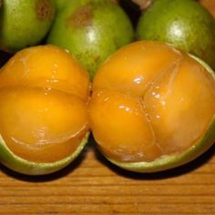 some green and yellow fruit sitting on top of a wooden table next to each other