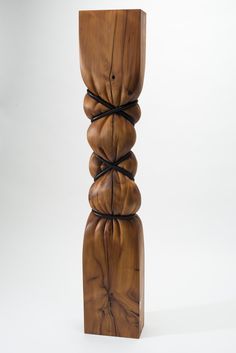 a tall wooden sculpture with four pieces of wood stacked on top of each other