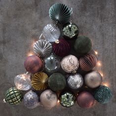 a christmas tree made out of glass balls and lights on the side of a concrete floor