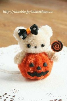 a small teddy bear holding a candy lollipop in its hand on a doily