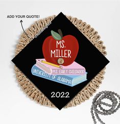 a black graduation cap with an apple and books on it next to a beaded bracelet