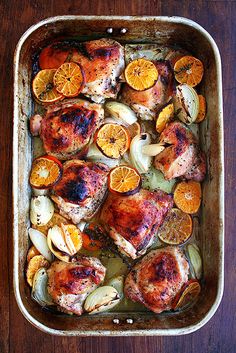 chicken and oranges in a casserole dish on a wooden table