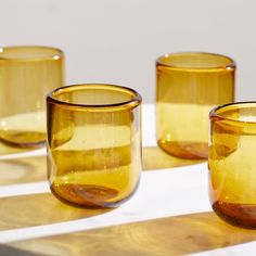 three yellow glass cups sitting on top of a table