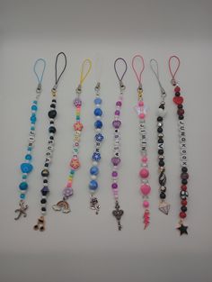 several necklaces are lined up on a white surface with beads and charms hanging from them