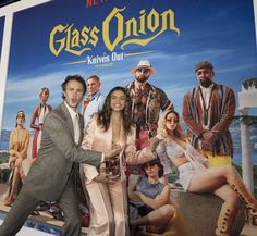 a man and woman posing in front of a poster for glass onion at an event