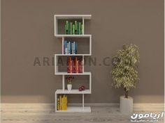 a white shelf with books on it next to a potted plant