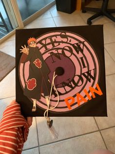 a person holding up a black and pink graduation cap