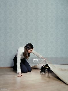 a woman kneeling on the floor looking at a toy car