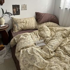 an unmade bed in a bedroom next to a table with a lamp on it