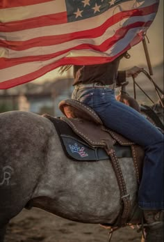 a woman riding on the back of a horse holding an american flag