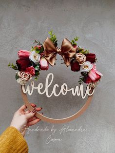 a person holding up a welcome sign with flowers on it