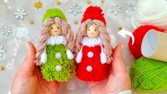 two small knitted dolls sitting next to balls of yarn