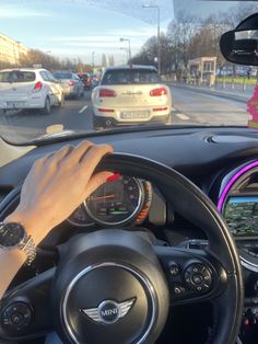 a person is driving their car on the street with other cars in the back ground