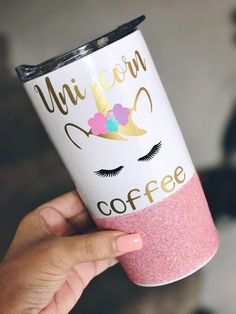 a person holding up a coffee cup with unicorn on it