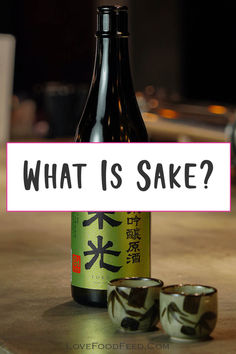 a bottle and two cups sitting on top of a table next to a sign that says what is sake?