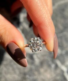 a woman's hand holding an engagement ring with a diamond on the middle finger