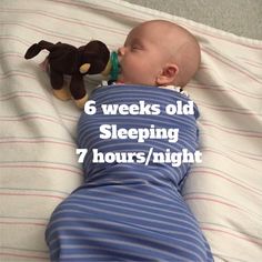 a baby laying on top of a bed with a stuffed animal next to it's head