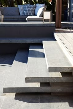 a couch and some stairs in front of a patio with pillows on the back ground