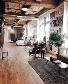 a living room filled with lots of furniture next to tall windows on the side of a wall